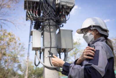 5G network engineer reviewing wireless infrastructure near a telecom tower