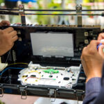 Fiber optic technician working on an outdoor cable box for broadband installation and testing