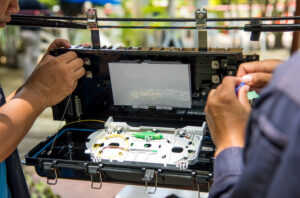 Fiber optic technician working on an outdoor cable box for broadband installation and testing
