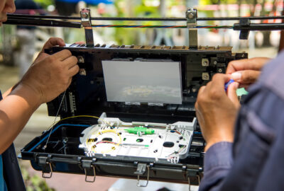 Fiber optic technician working on an outdoor cable box for broadband installation and testing