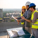 Site acquisition staffing team reviewing wireless deployment plans near telecom infrastructure