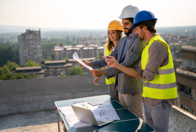 Site acquisition staffing team reviewing wireless deployment plans near telecom infrastructure