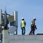 Tower construction manager staffing support for wireless crews reviewing build plans near a telecom tower