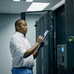 DC power technician inspecting UPS battery systems in a data center power room