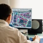 Fiber asset specialist reviewing GIS maps and as-built records for a broadband network