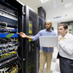 Data center maintenance manager reviewing critical facility systems with a technician