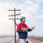 OSP field engineer reviewing fiber route conditions near utility poles