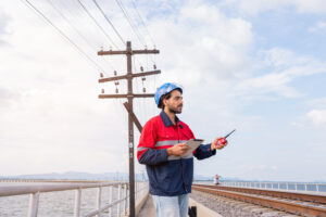 OSP field engineer reviewing fiber route conditions near utility poles
