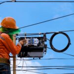 Telecom field technician inspecting a utility pole for an aerial broadband build