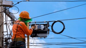 Telecom field technician inspecting a utility pole for an aerial broadband build