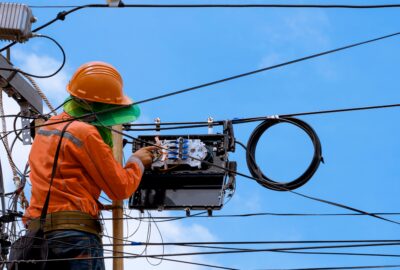 Telecom field technician inspecting a utility pole for an aerial broadband build