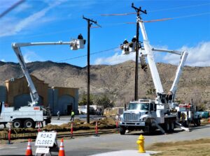 Aerial fiber lineman in a bucket truck installing fiber optic cable on a utility pole during a broadband build