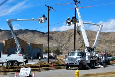 Aerial fiber lineman in a bucket truck installing fiber optic cable on a utility pole during a broadband build