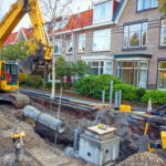 Fiber construction crew placing orange conduit along a residential street during a fiber overbuild project