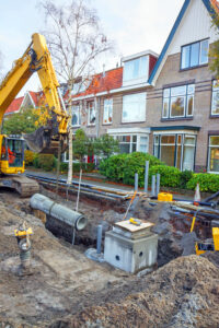 Fiber construction crew placing orange conduit along a residential street during a fiber overbuild project