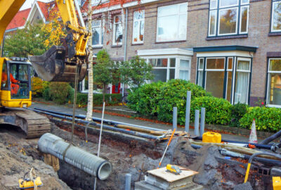Fiber construction crew placing orange conduit along a residential street during a fiber overbuild project