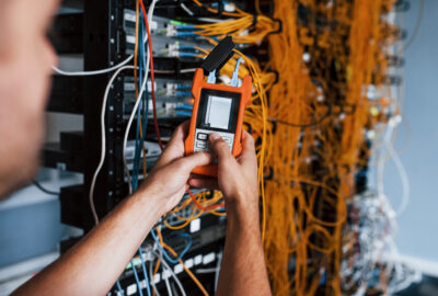 Fiber test technician using an optical test set to check fiber optic links before network acceptance